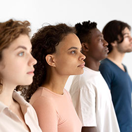 Cuatro jóvenes de perfiles diversos mirando hacia adelante sobre fondo blanco